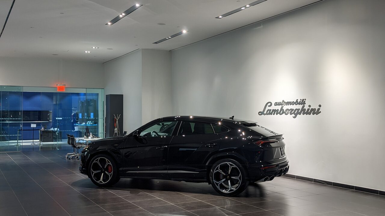 Lamborghini Urus preto estacionado num showroom claro, com a tampa do porta-malas fechada